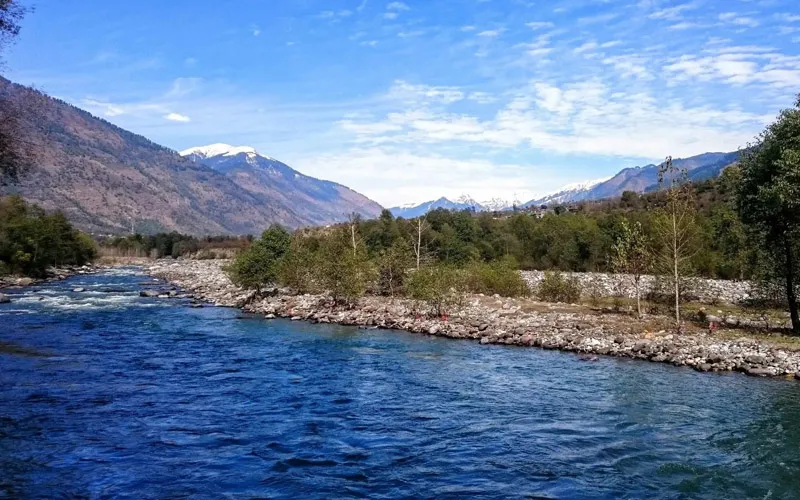 Clear blue waters of Beas River flowing through Kullu valley with mountain backdrop