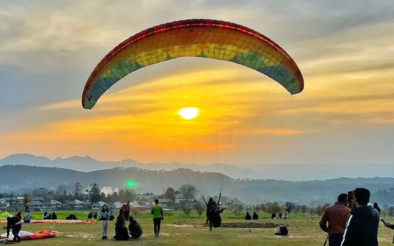 Paraglider flying against golden sunset sky over Bir Billing paragliding site