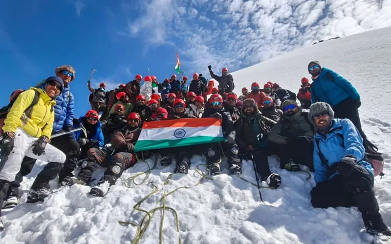 Mountaineering expedition team holding the Indian tricolor flag on the snow-covered summit of Friendship Peak