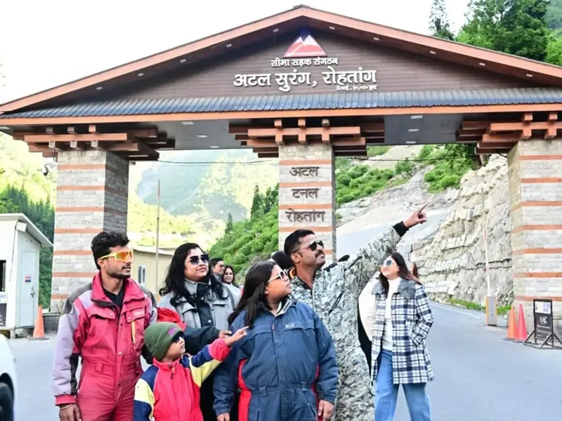 Family posing in winter snow suits in front of the Atal Tunnel Rohtang south portal entrance