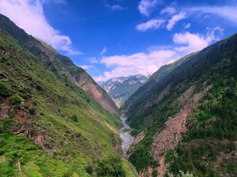 Scenic panorama of a deep Himalayan river valley bordered by rugged forested peaks