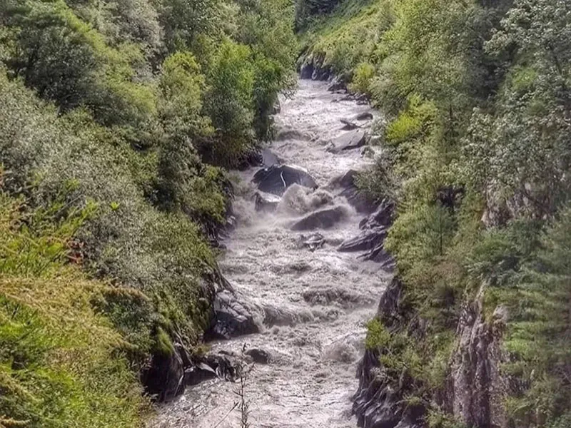Whitewater mountain river coursing through rocky gorges and lush green valley slopes