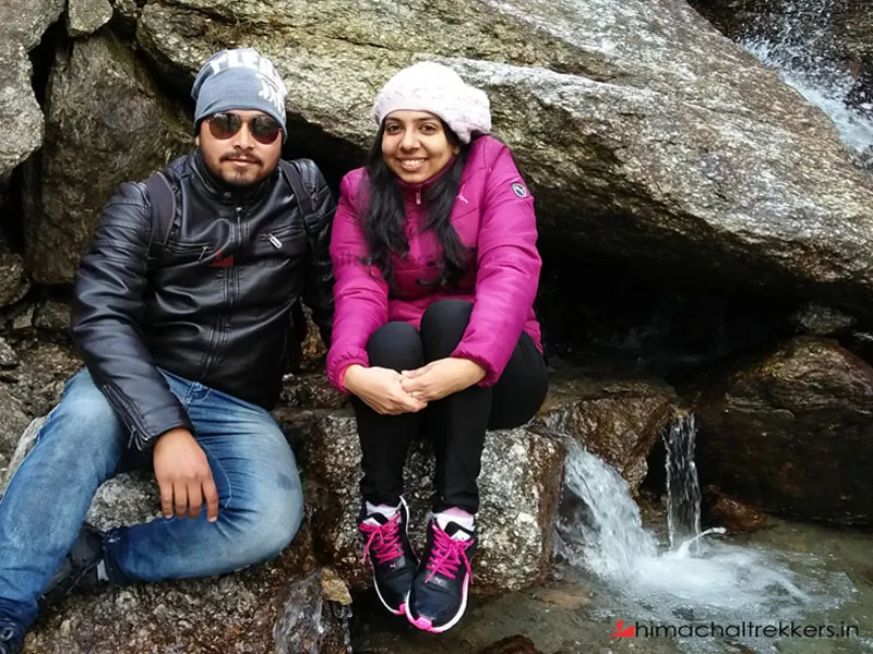 Hikers relaxing by a natural fresh mountain stream on Barot Valley trek