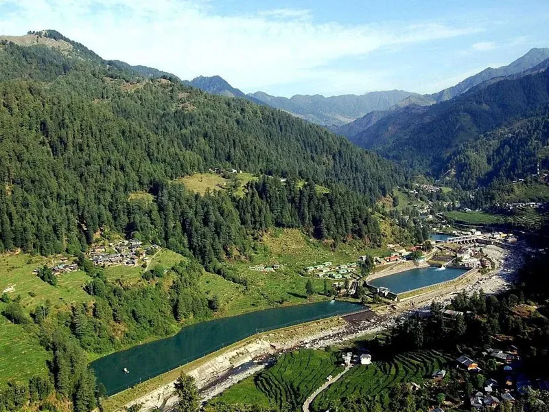 Aerial panoramic view of Barot Valley reservoir and Uhl river surrounded by dense green pine forests