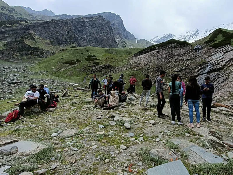 Group of trekkers resting on a boulder-strewn moraine near Beas Kund
