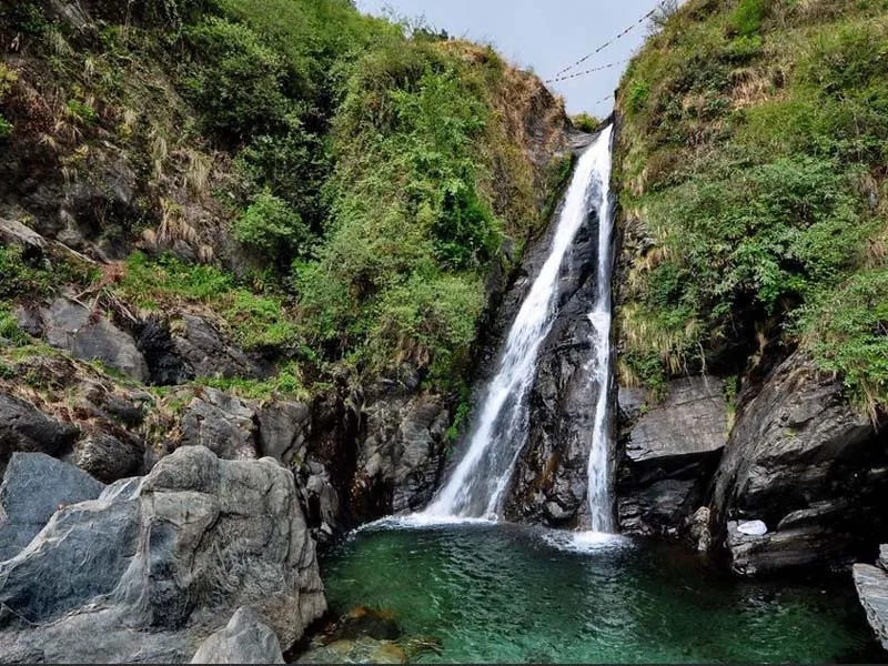 Natural mountain stream of Bhagsu Waterfall gushing over dark rocks near McLeodganj