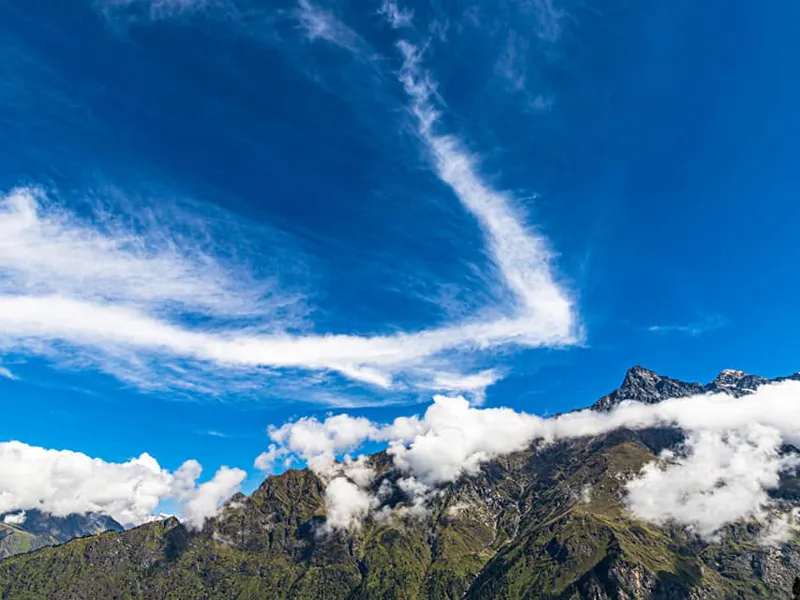 Striking cloud patterns in deep blue sky over rugged Himalayan mountain peaks