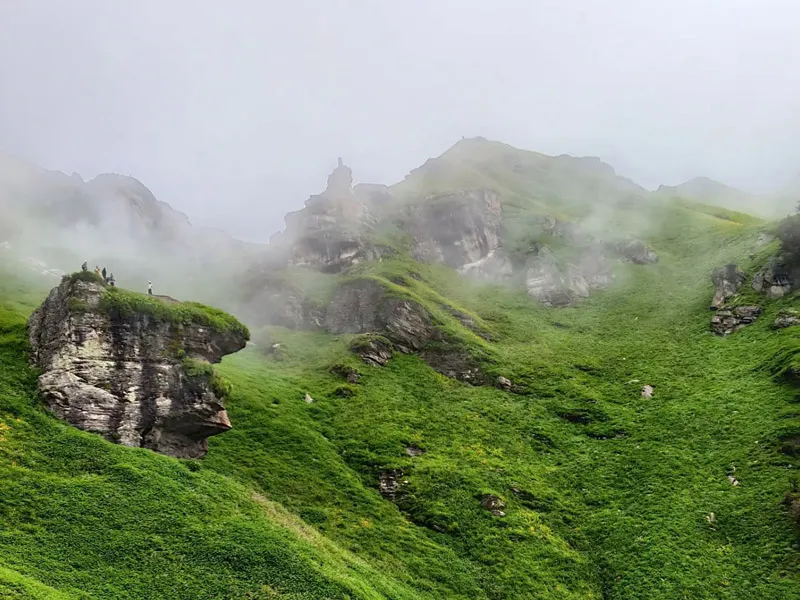 Misty green alpine ridge and rocky outcrops on the Chandrakhani Pass trail