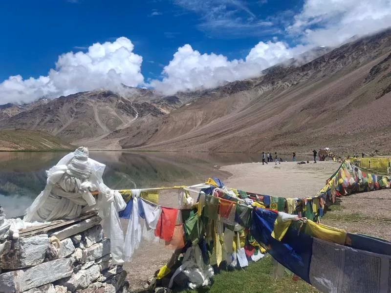 Colorful Buddhist prayer flags strung along the sacred shores of crescent-shaped Chandratal Lake