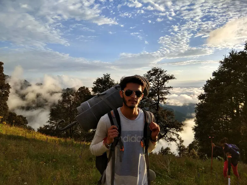 Backpacker walking along an alpine ridge with clouds floating below in the valley
