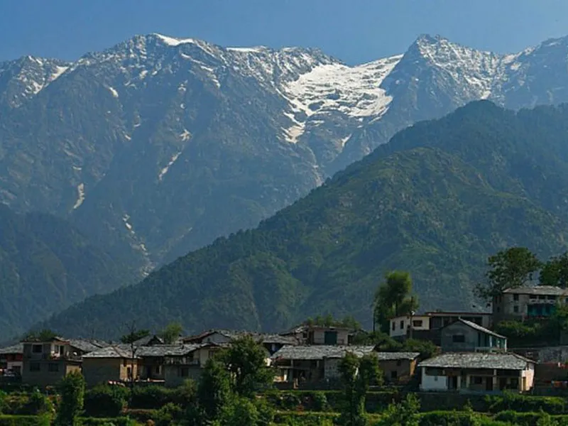 Scenic traditional Himalayan village houses situated beneath soaring snow-clad mountain ridges