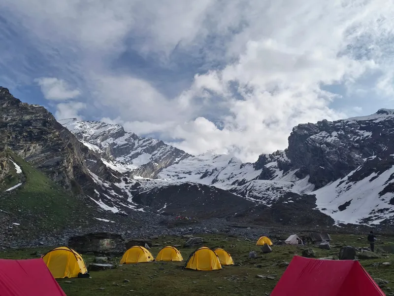 Friendship Peak base camp with yellow dome tents facing snow-streaked mountain walls