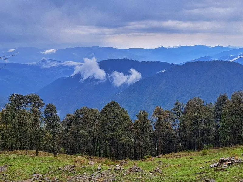 Scenic panorama of misty blue mountain ranges and pine-covered ridges from Jalori Pass near Jibhi