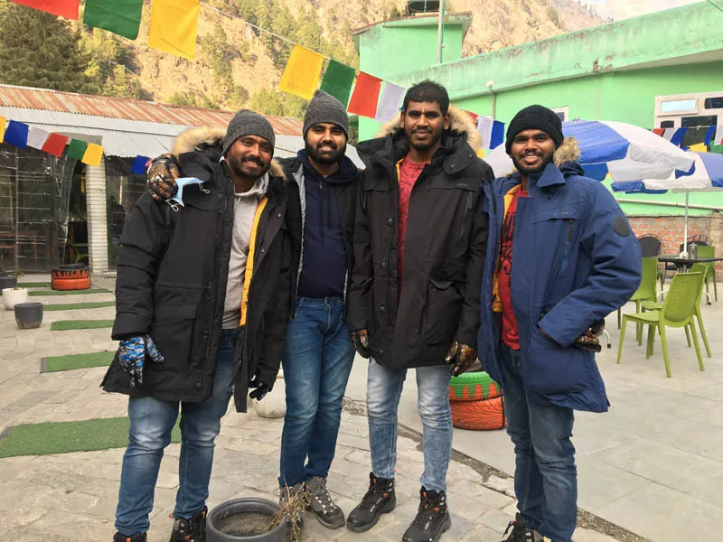 Group of friends posing in warm winter jackets outside a cafe at Kheerganga base