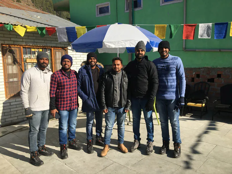 Trekkers gathered outside a local mountain homestay with colorful prayer flags in Kheerganga