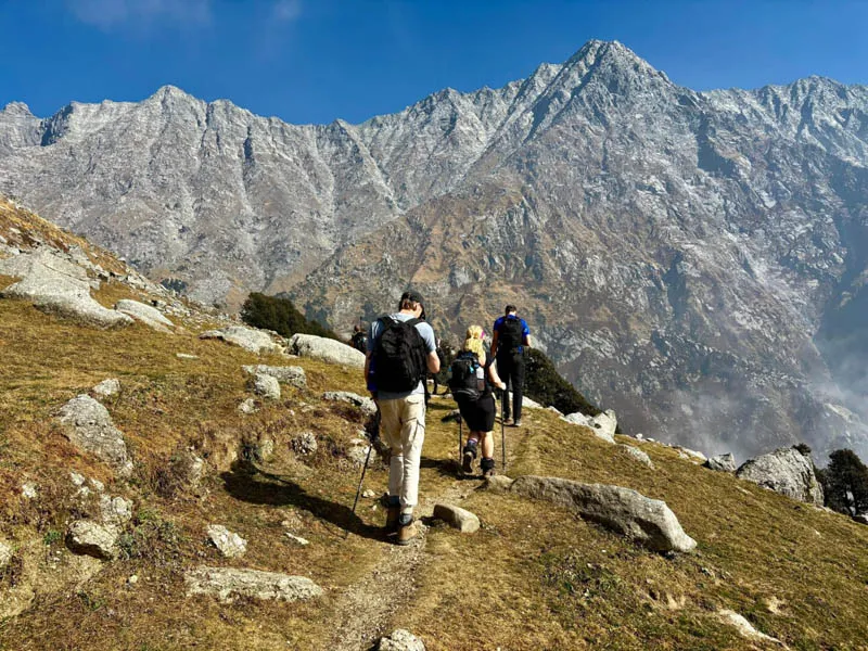 Trekkers ascending a high-altitude rocky ridge facing towering rocky Himalayan mountains