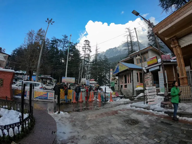 Tourists strolling along snow-lined street and shops near Manali
