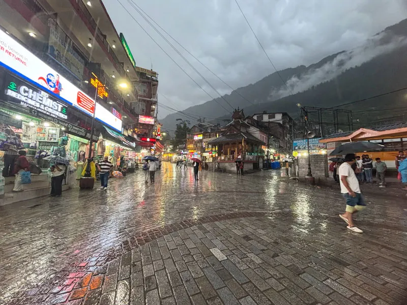 Wet cobblestone pavement reflecting evening shop lights on Mall Road Shimla after rainfall