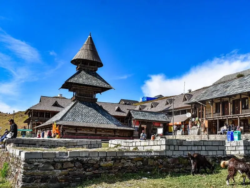 Three-tiered wooden pagoda architecture of historic Prashar Rishi Temple with slate stone courtyard