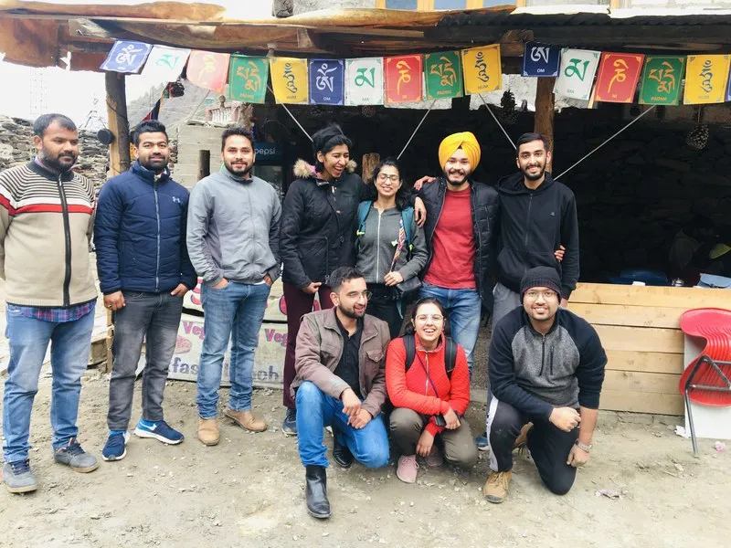 Trekking group posing together outside a rustic mountain dhaba along Prashar Lake trail