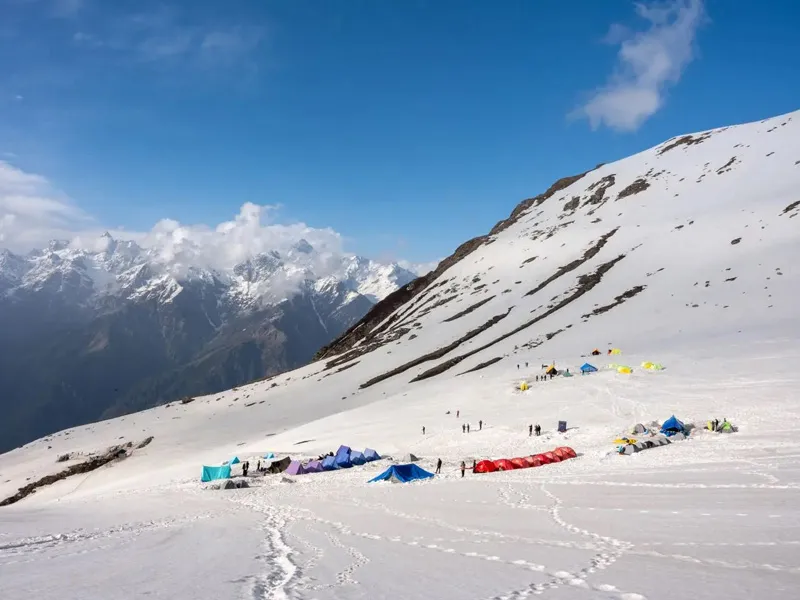 Sar Pass snow campsite with colorful tents pitched on wide snowy slopes surrounded by high peaks