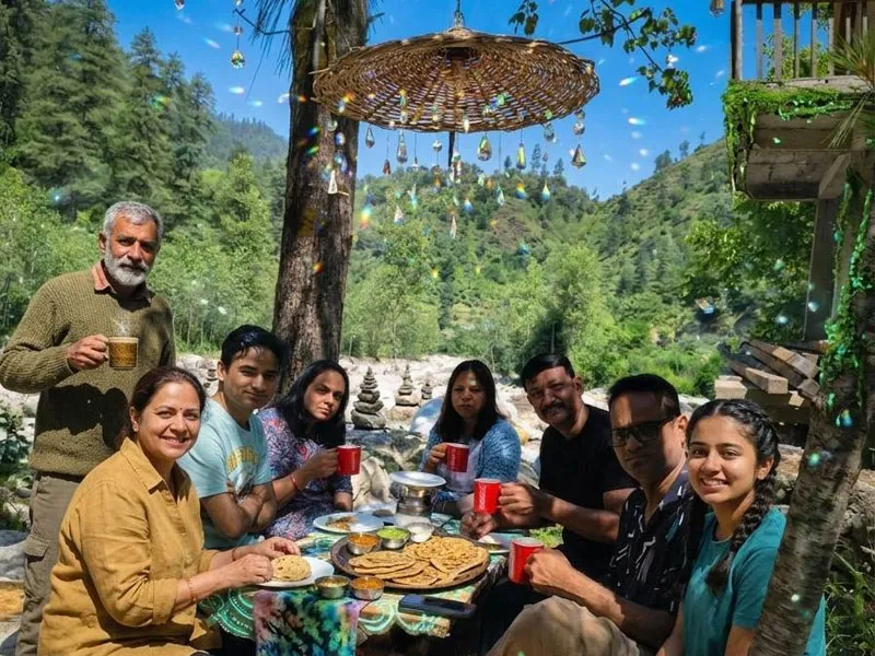 Family enjoying lunch and drinks at a scenic riverside cafe surrounded by nature in Tirthan Valley
