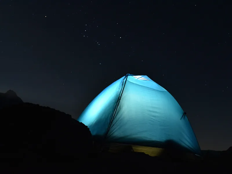 Glowing illuminated blue camping tent under the night sky at Triund top