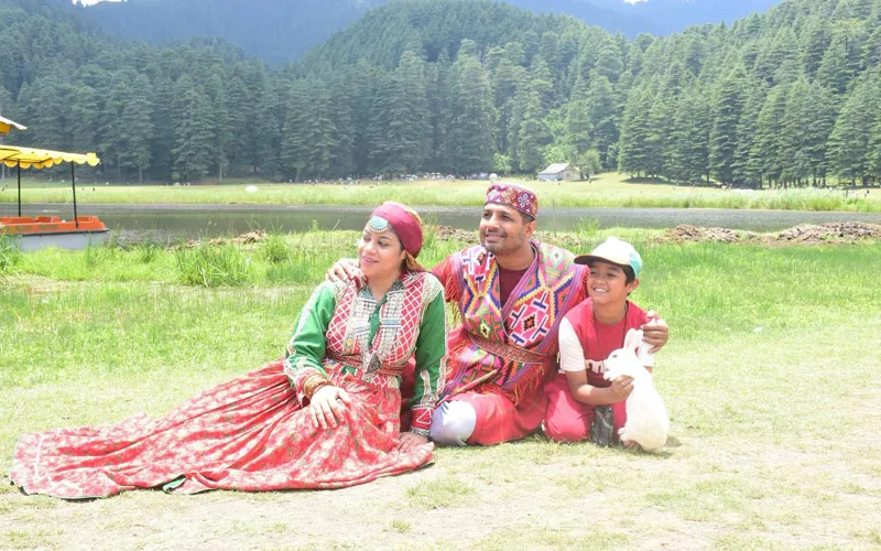 Family posing in traditional vibrant Himachali attire on the green meadows of Khajjiar near Dalhousie