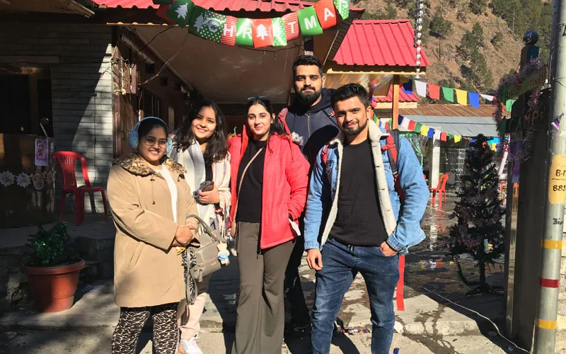 Group of young travelers smiling together outside a vibrant village cafe in Kasol Parvati Valley