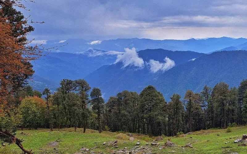 Panoramic vista of blue mountain ranges and evergreen pine ridges along Serolsar Lake trail