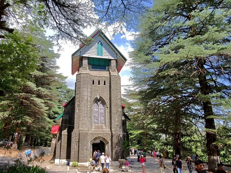 Historic stone bell tower of St. John in the Wilderness Church surrounded by deodar pine trees in Dharamshala