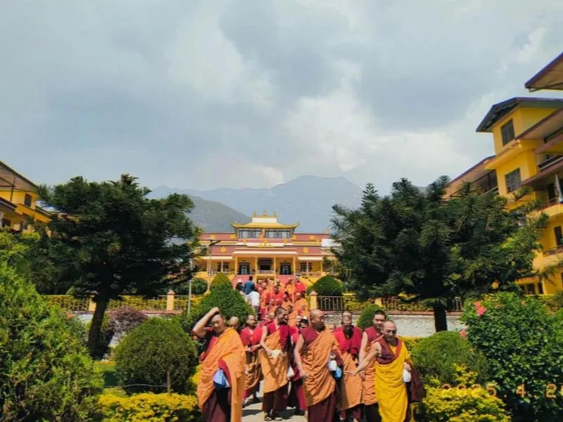 Tibetan Buddhist monks walking in the courtyard of an ornate monastery in McLeod Ganj Dharamshala
