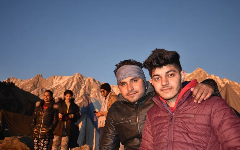 Young friends relaxing outdoors during sunset on the Triund ridge trek